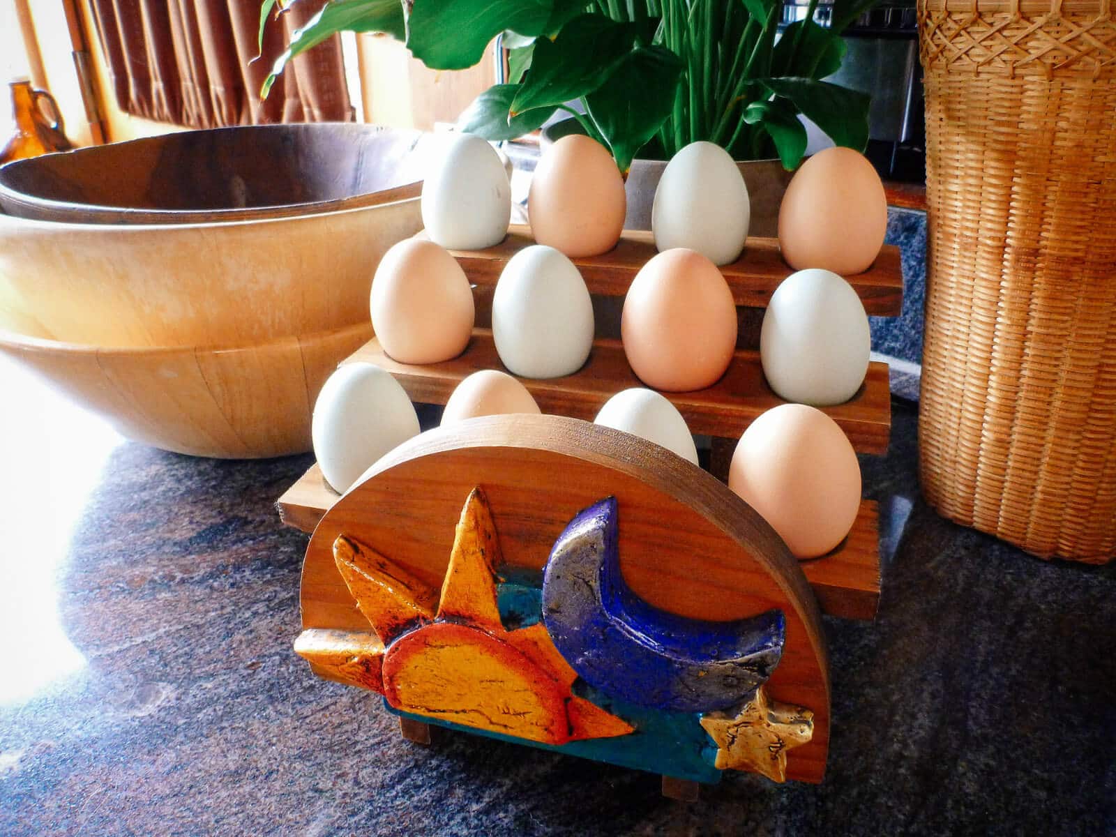Backyard eggs stored in a wooden egg holder on the counter