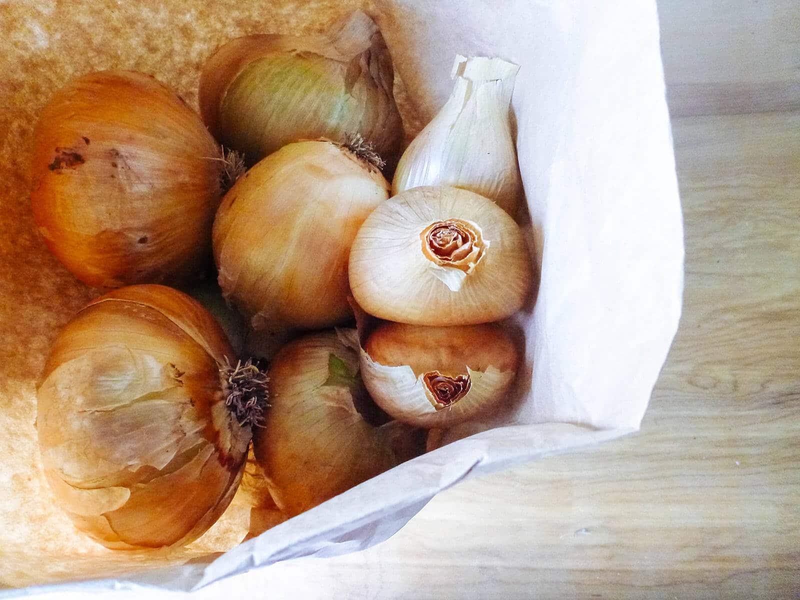 Yellow onions stored in brown paper bag