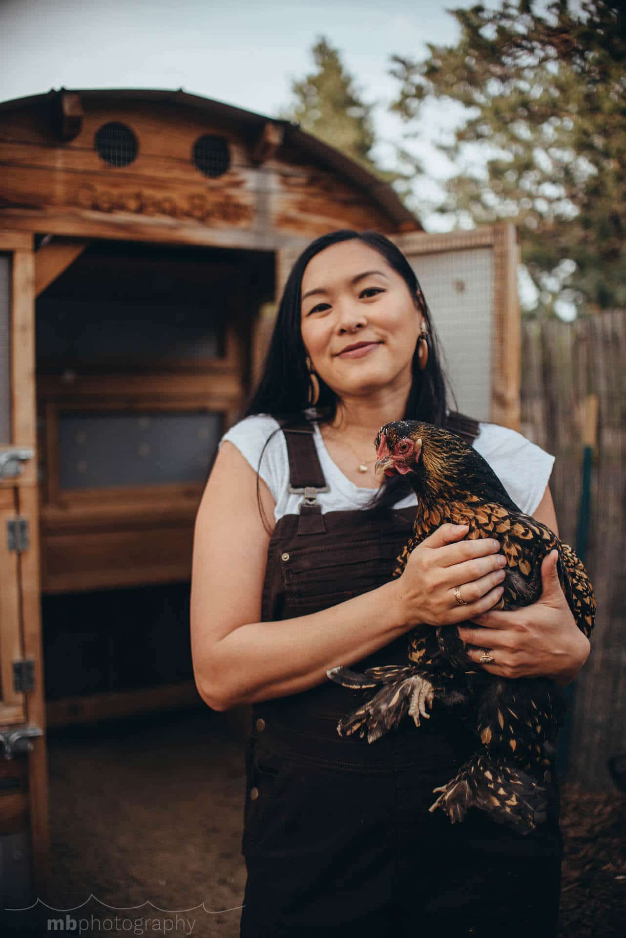Garden Betty holding a Golden Laced Cochin chicken in front of the coop
