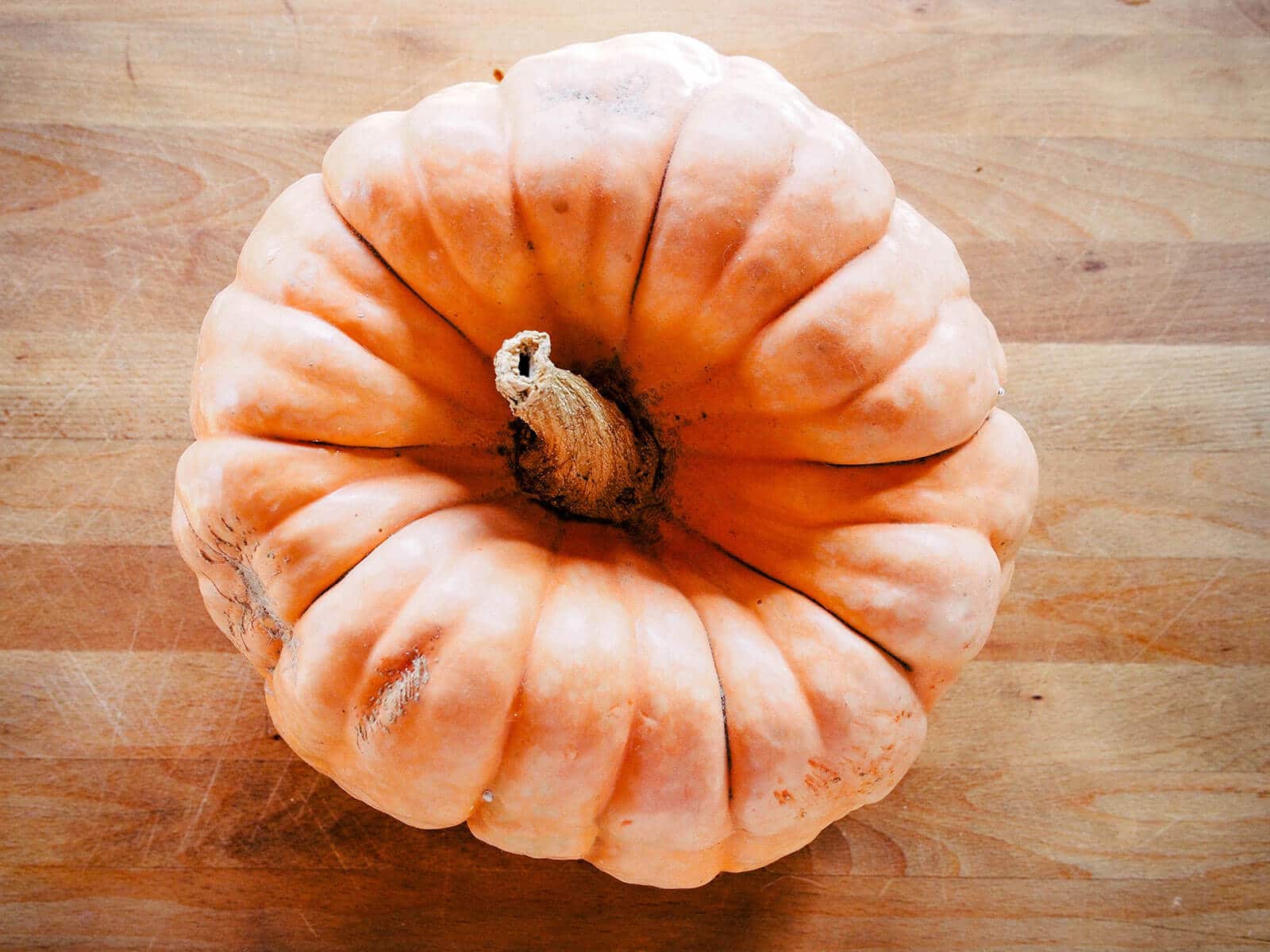 Overhead view of a ribbed pumpkin on a butcher block counter