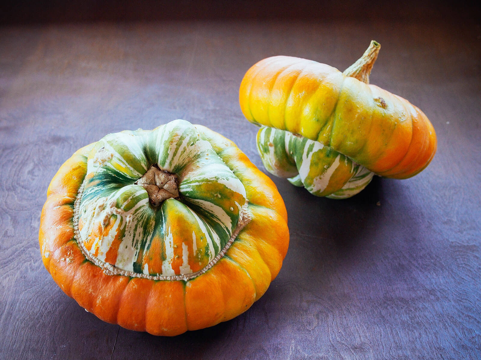 Two turban squash sitting on a wooden table