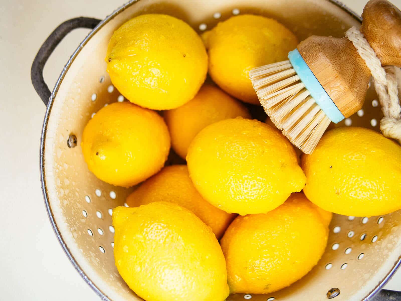 Organic lemons being washed and scrubbed in a colander