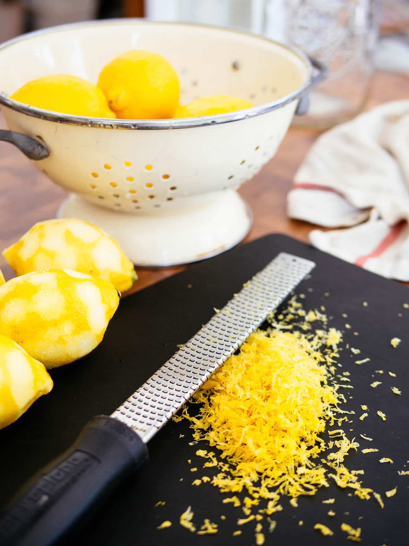 Freshly zested lemons on a cutting board with a Microplane