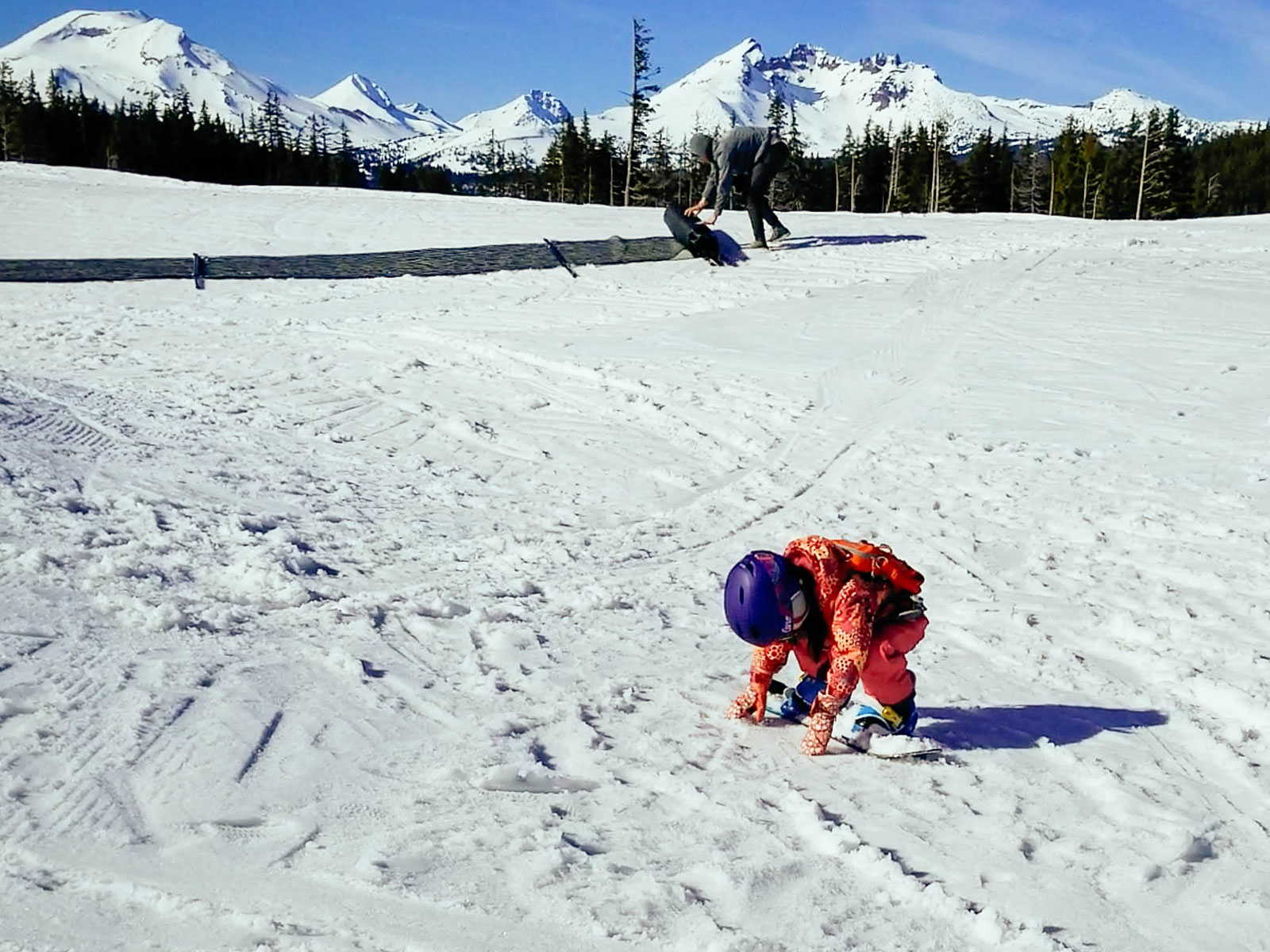 A 3-year-old toddler practicing toeside slipping on her snowboard