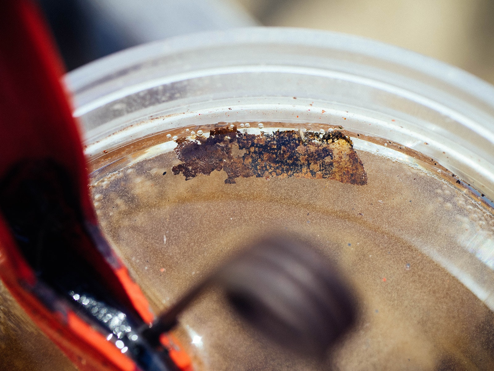 A piece of loosened rust floating in a jar of vinegar