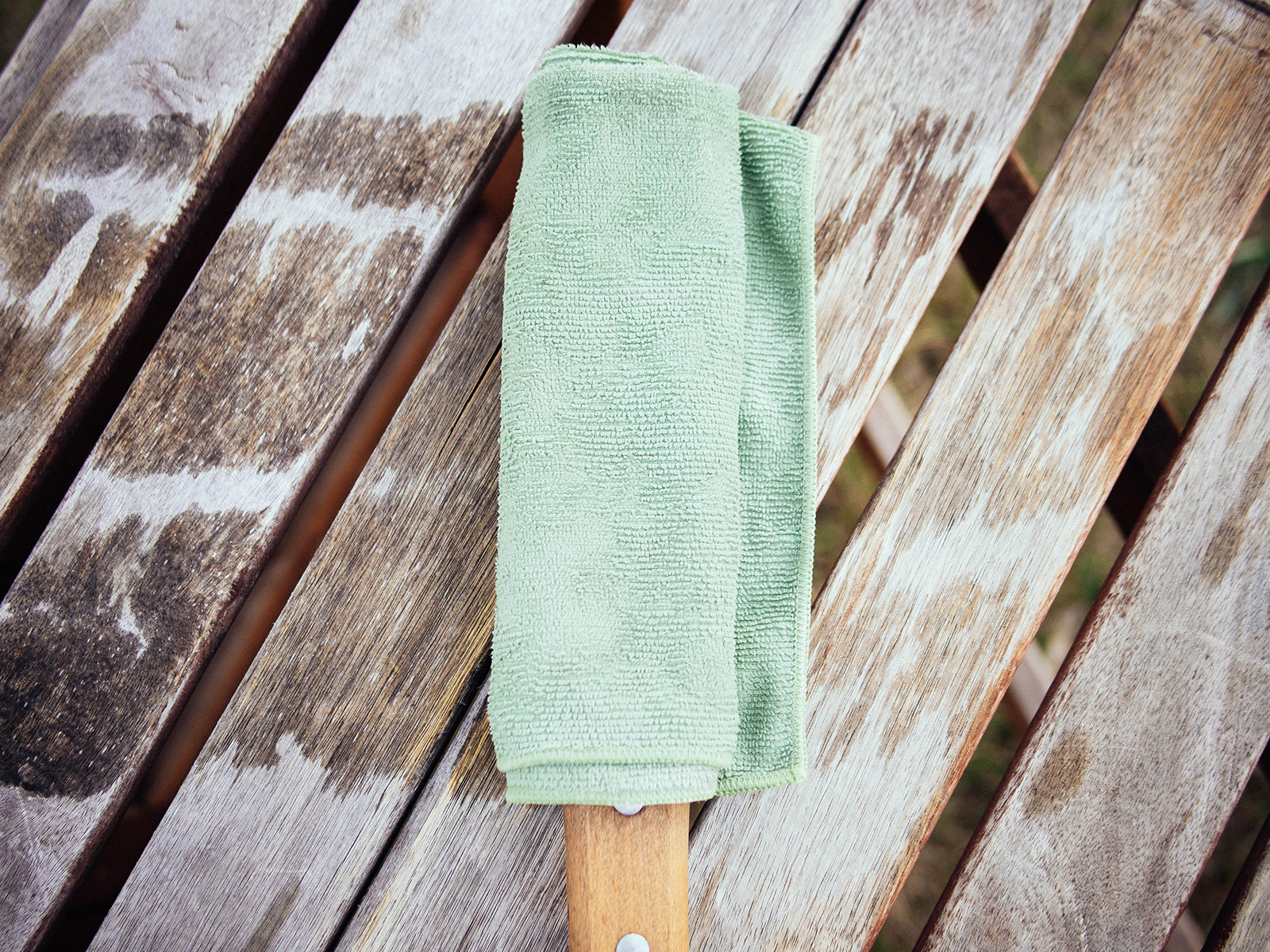 A garden tool wrapped in a vinegar-soaked green towel for rust removal