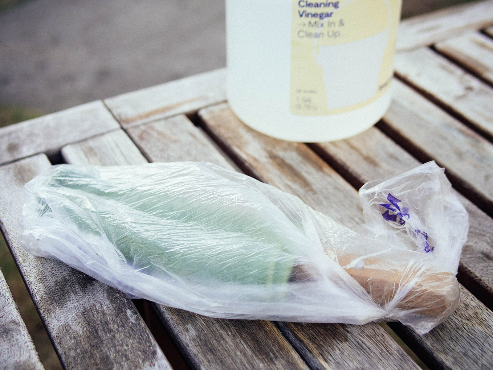 A hand tool wrapped in a green vinegar-soaked towel and placed inside a plastic bag for rust removal