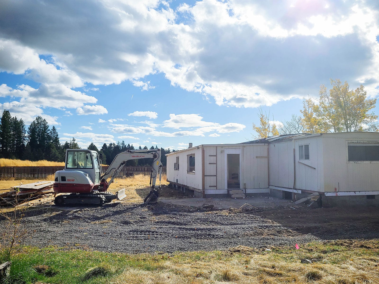 A mini excavator next to an older manufactured home