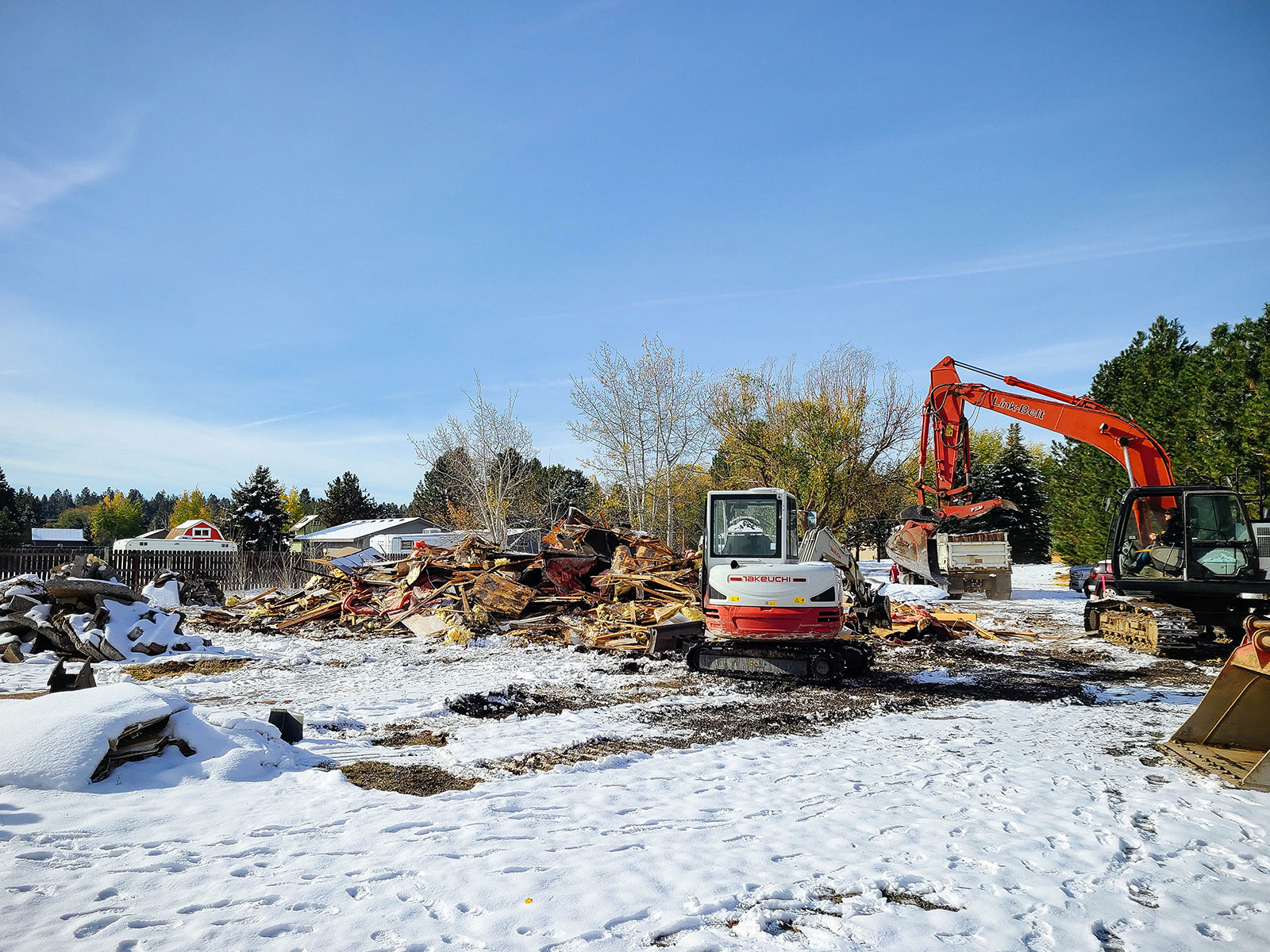 Excavators next to a pile of debris from a demolished home