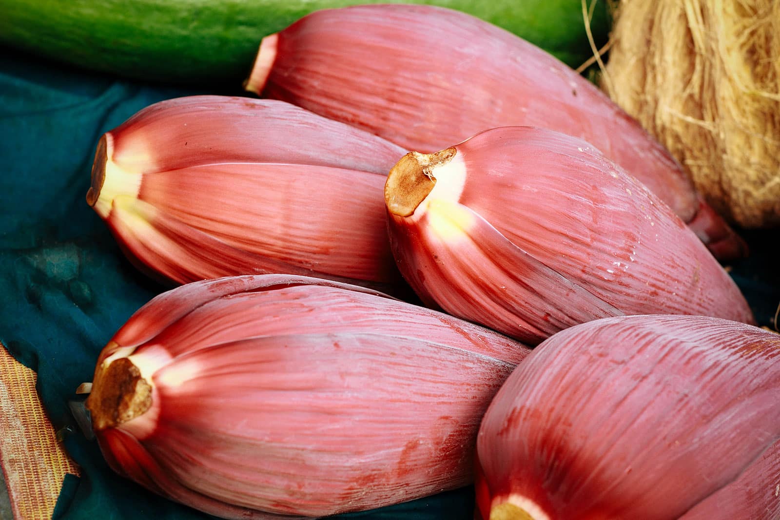 Maroon-colored banana flowers piled together at a market