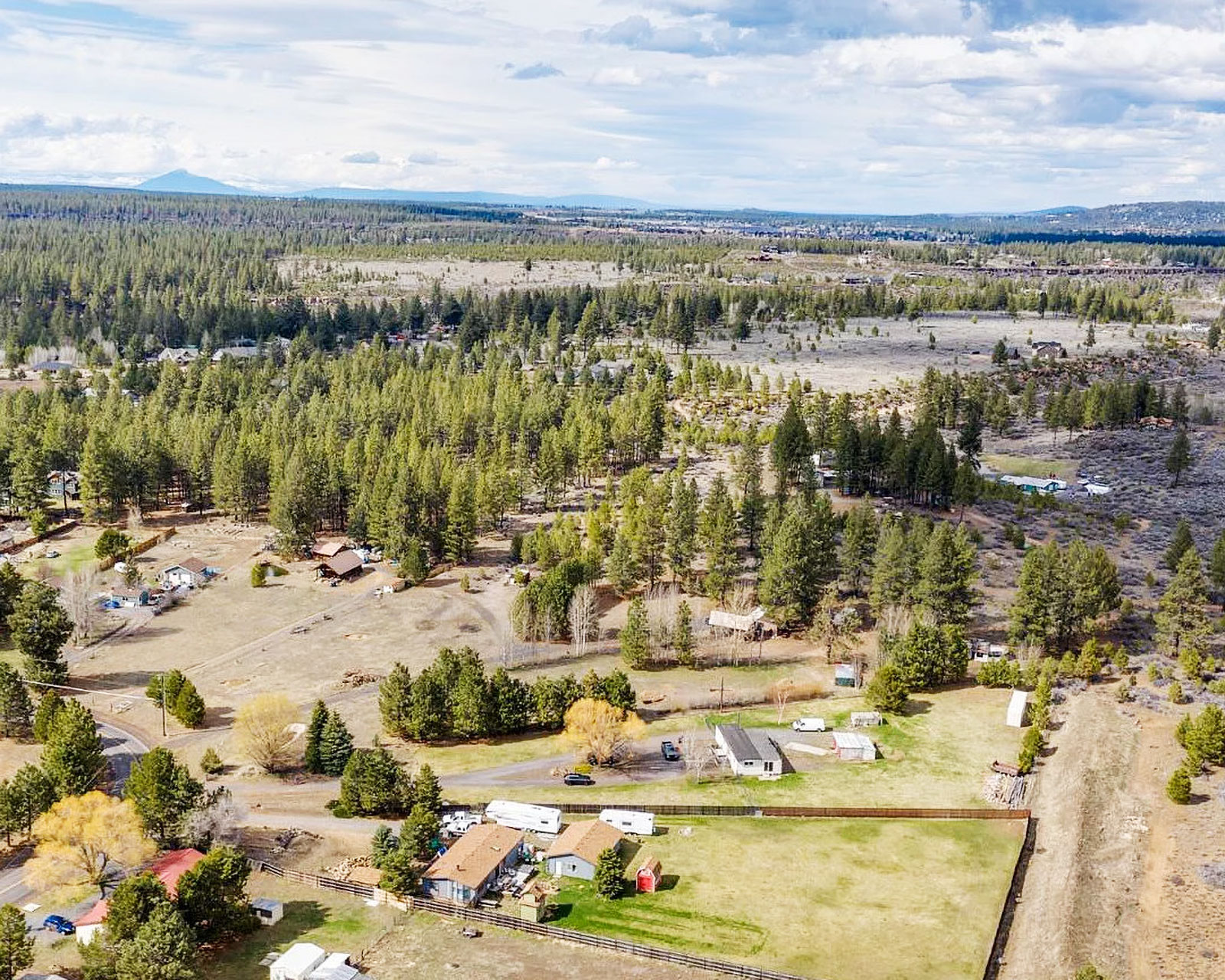 Aerial view of a rural neighborhood with conifers and pastures
