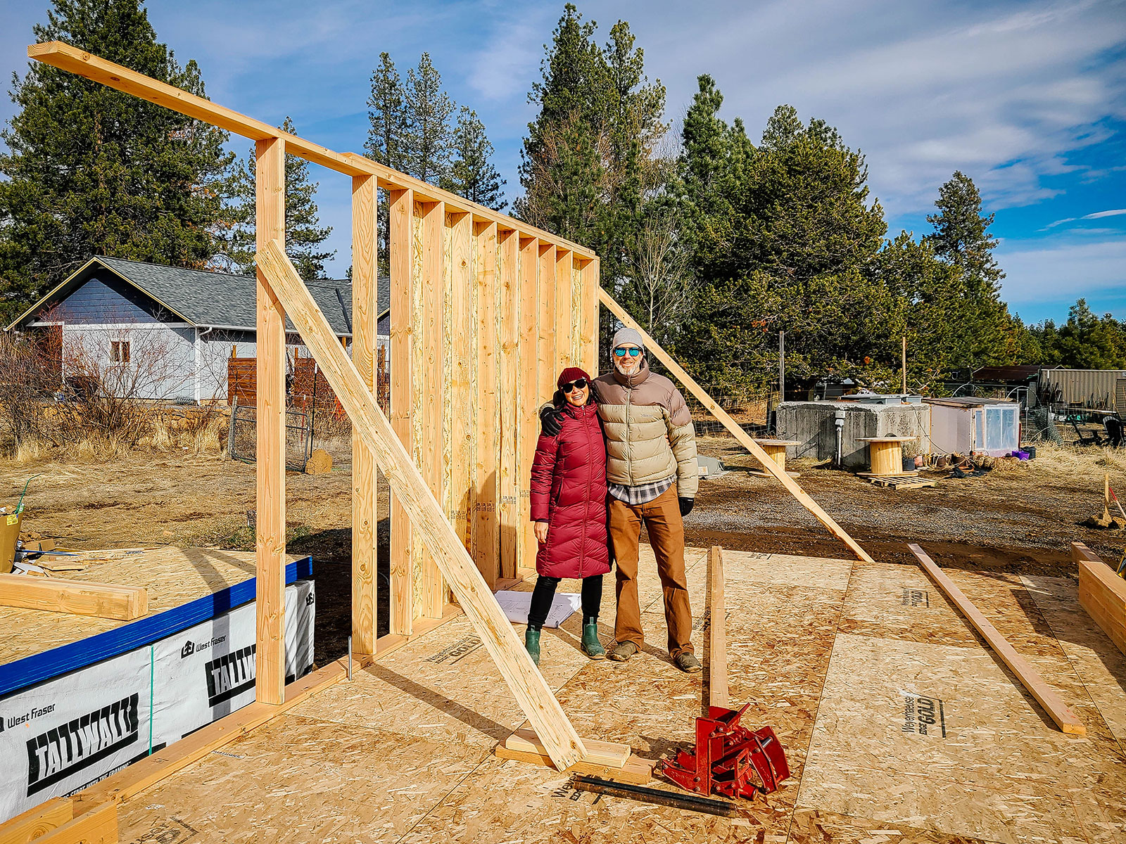 Man and woman standing in front of a framed house wall on a construction site