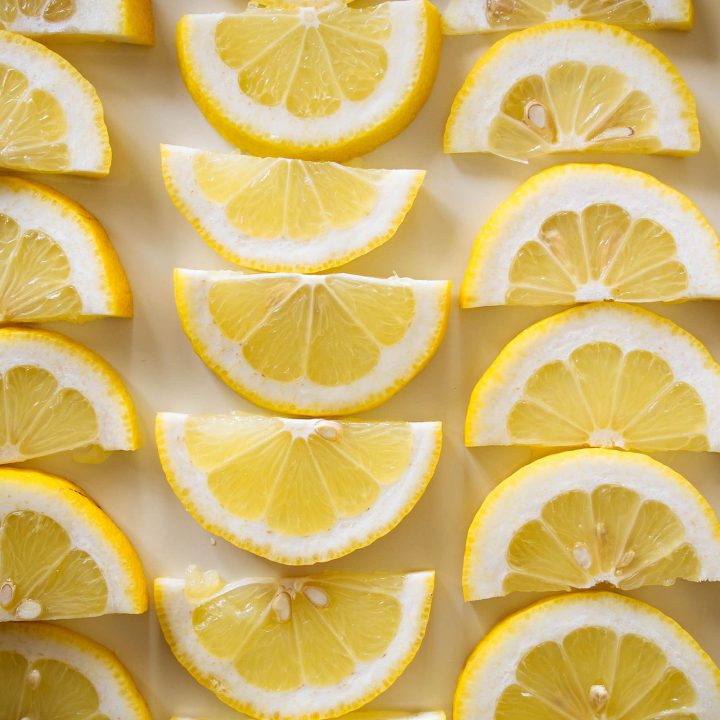 Overhead shot of lemon half-slices arranged in rows on a baking tray