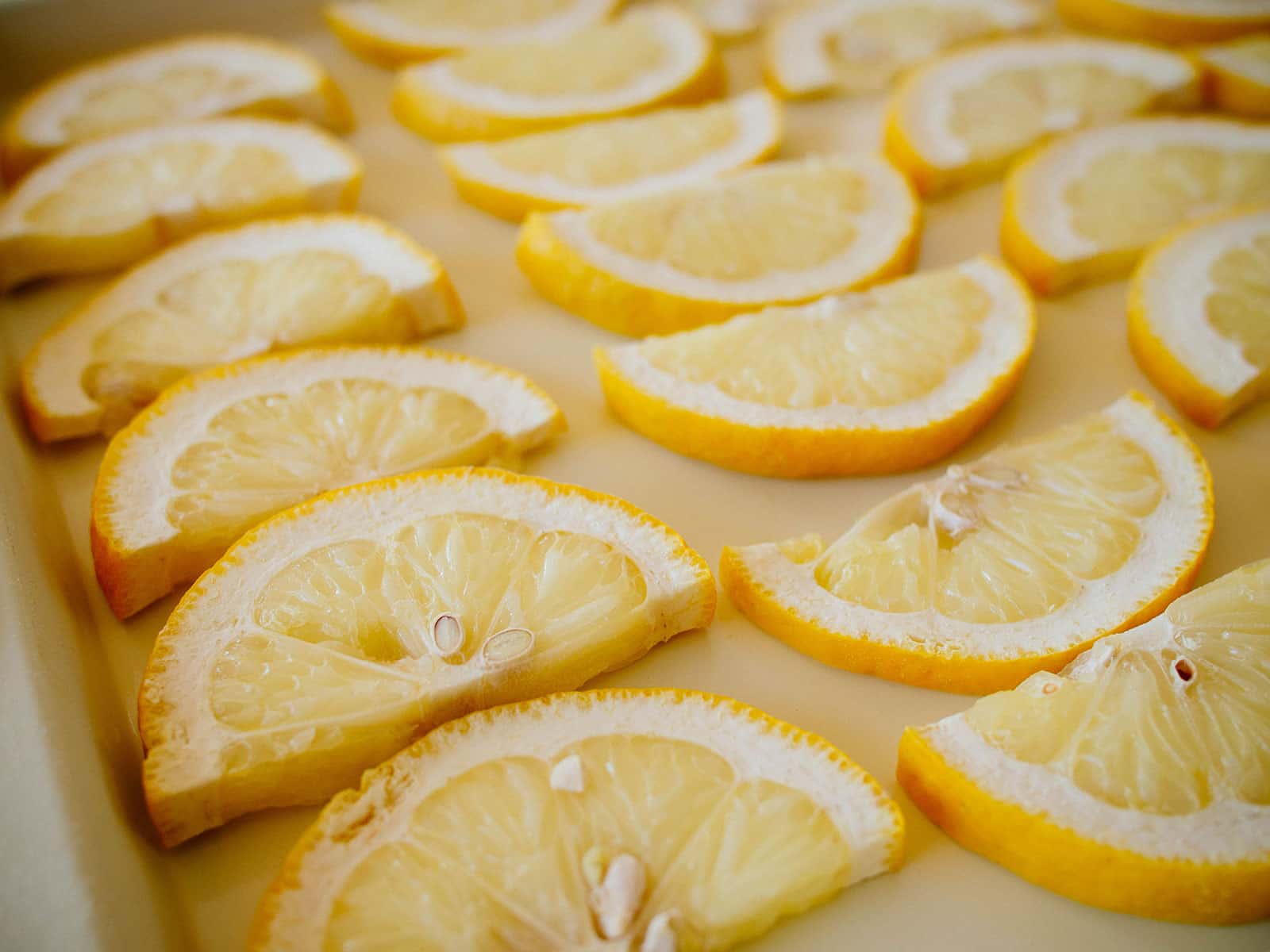 Frozen half slices of lemons arranged on a cream-colored baking tray