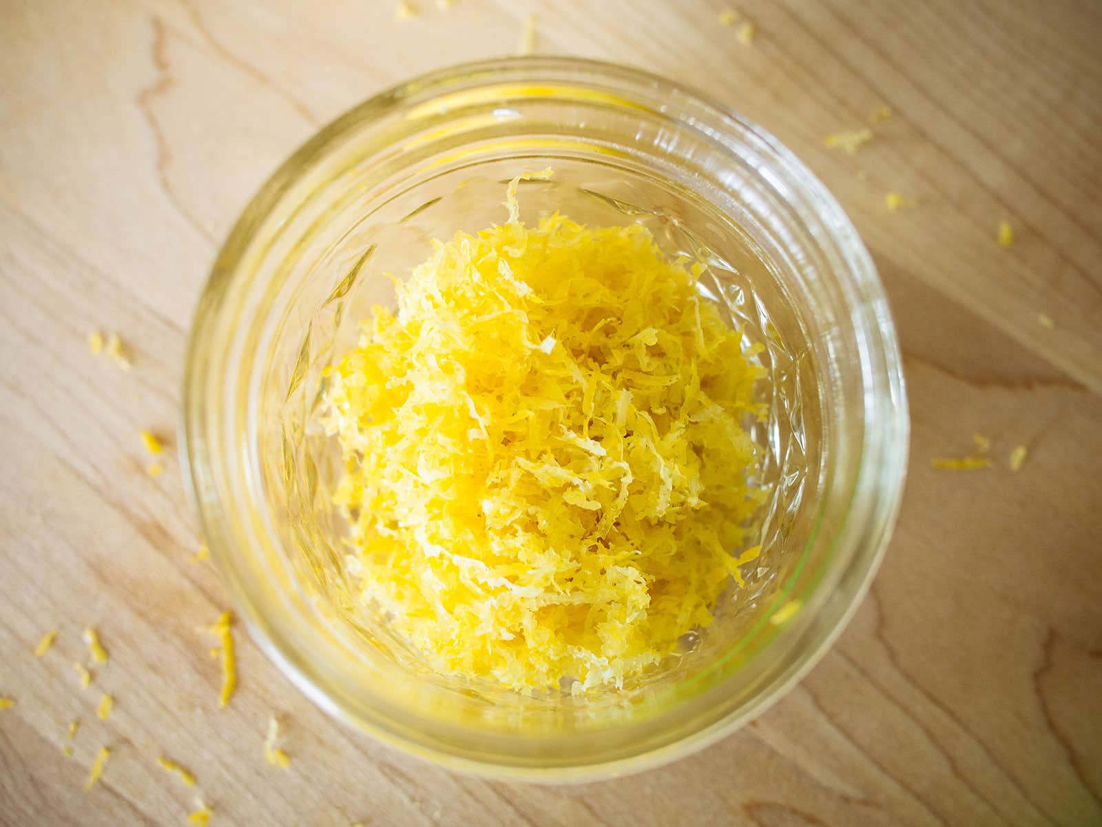 Closeup of fresh lemon zest in a glass jar shot on a wooden surface