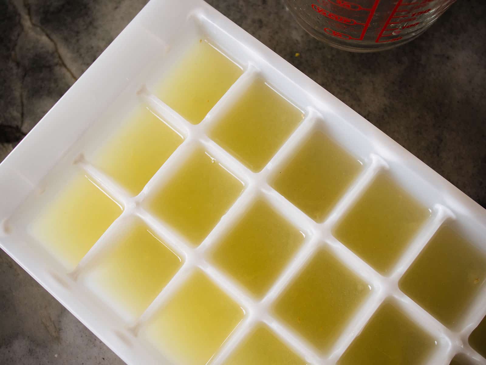 Overhead shot of a white ice cube tray filled with lemon juice