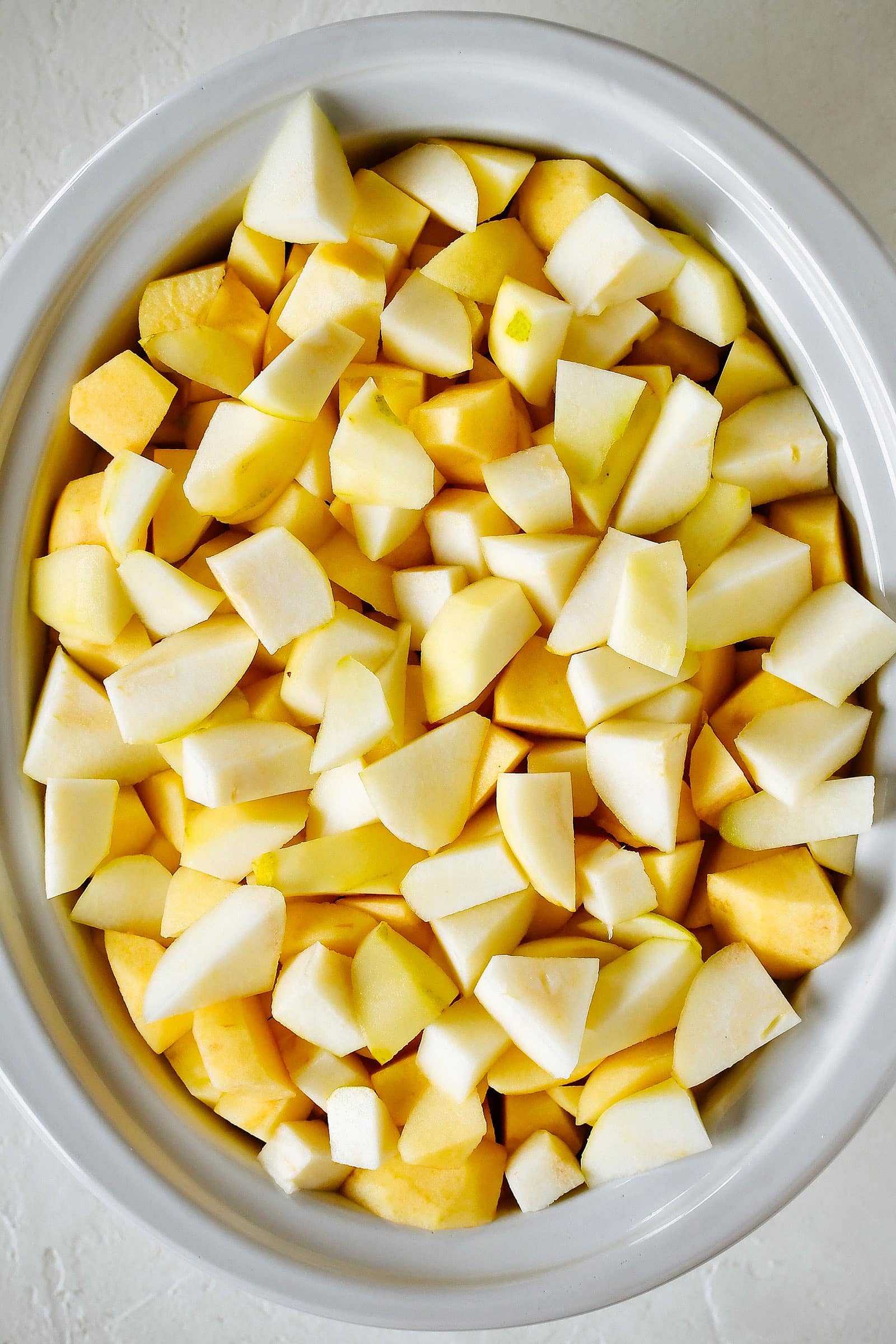 Overhead shot of a crockpot filled to the brim with peeled and chopped apples and pears