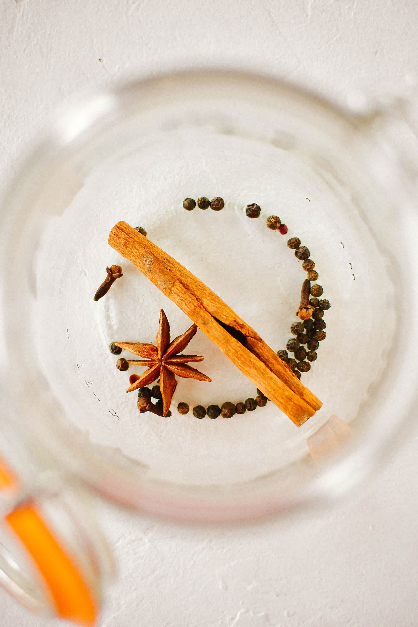 Bowl of water with peppercorns, cloves, star anise, and a cinnamon stick in it