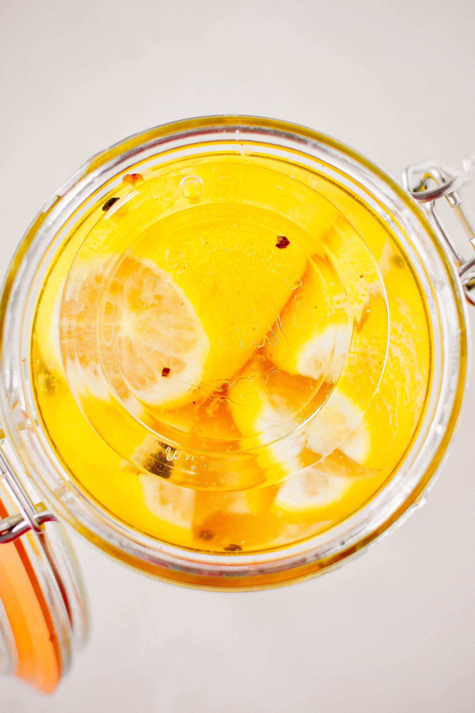 Close-up view of a glass weight inside a jar, keeping lemons submerged in brine