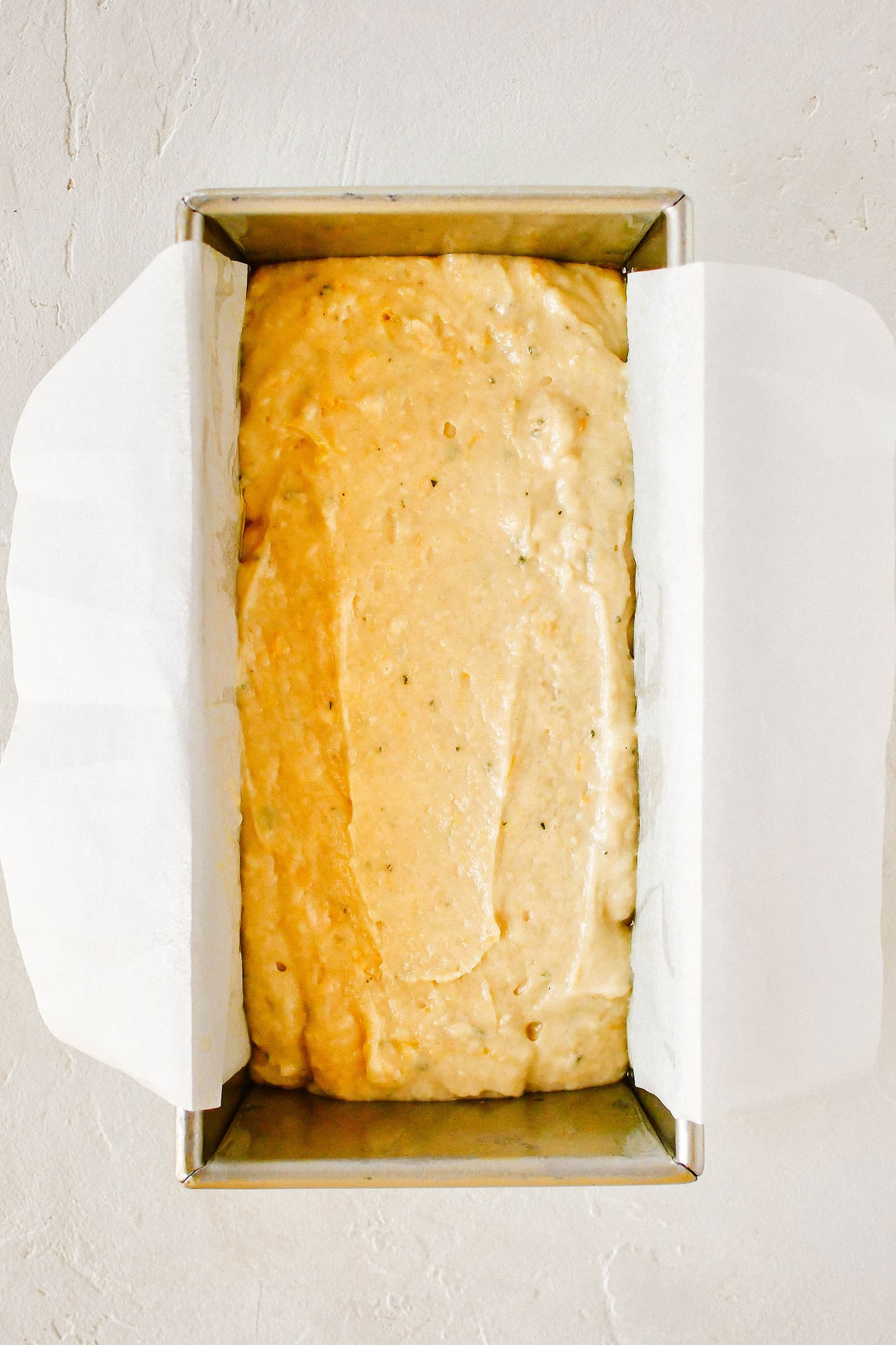 Parchment-lined loaf pan filled with bread batter