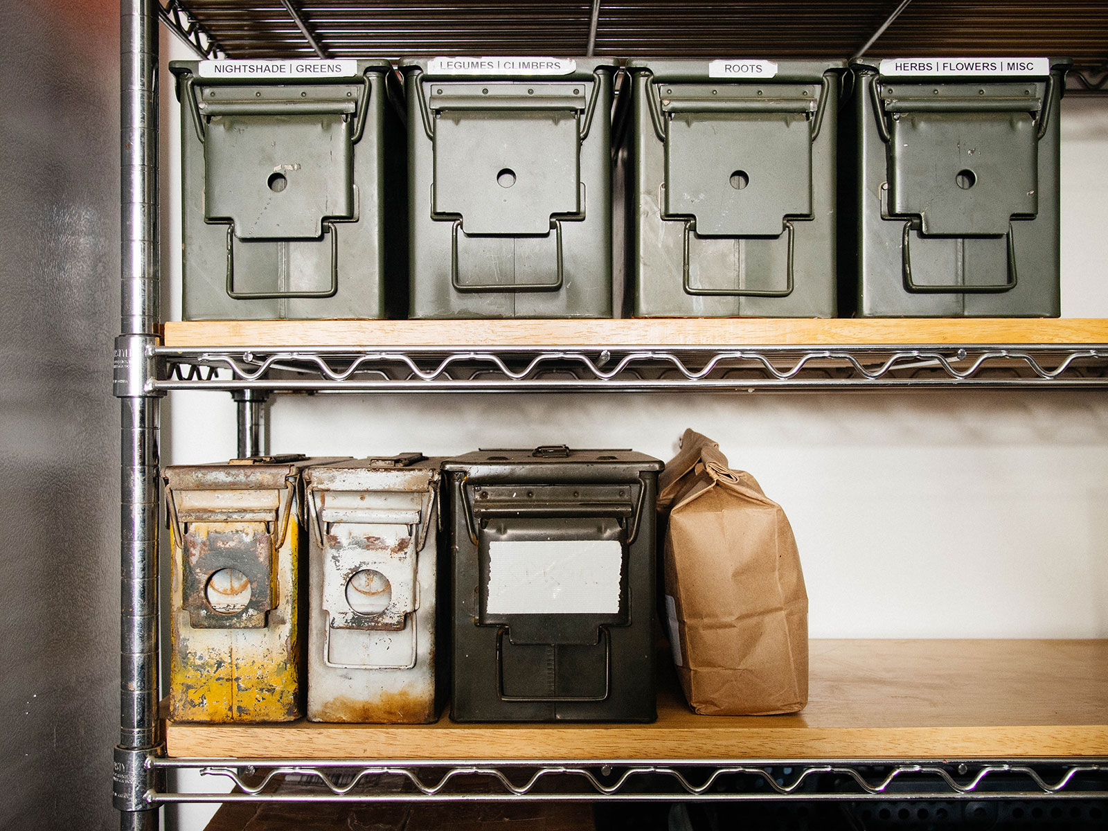 Metal ammo cans on wooden shelves in a workbench