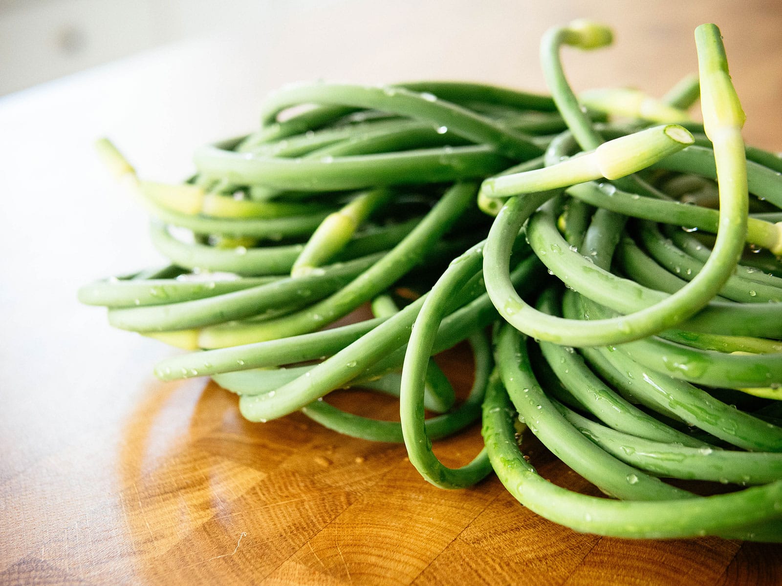 Close-up of washed garlic scapes with water droplets on the stems