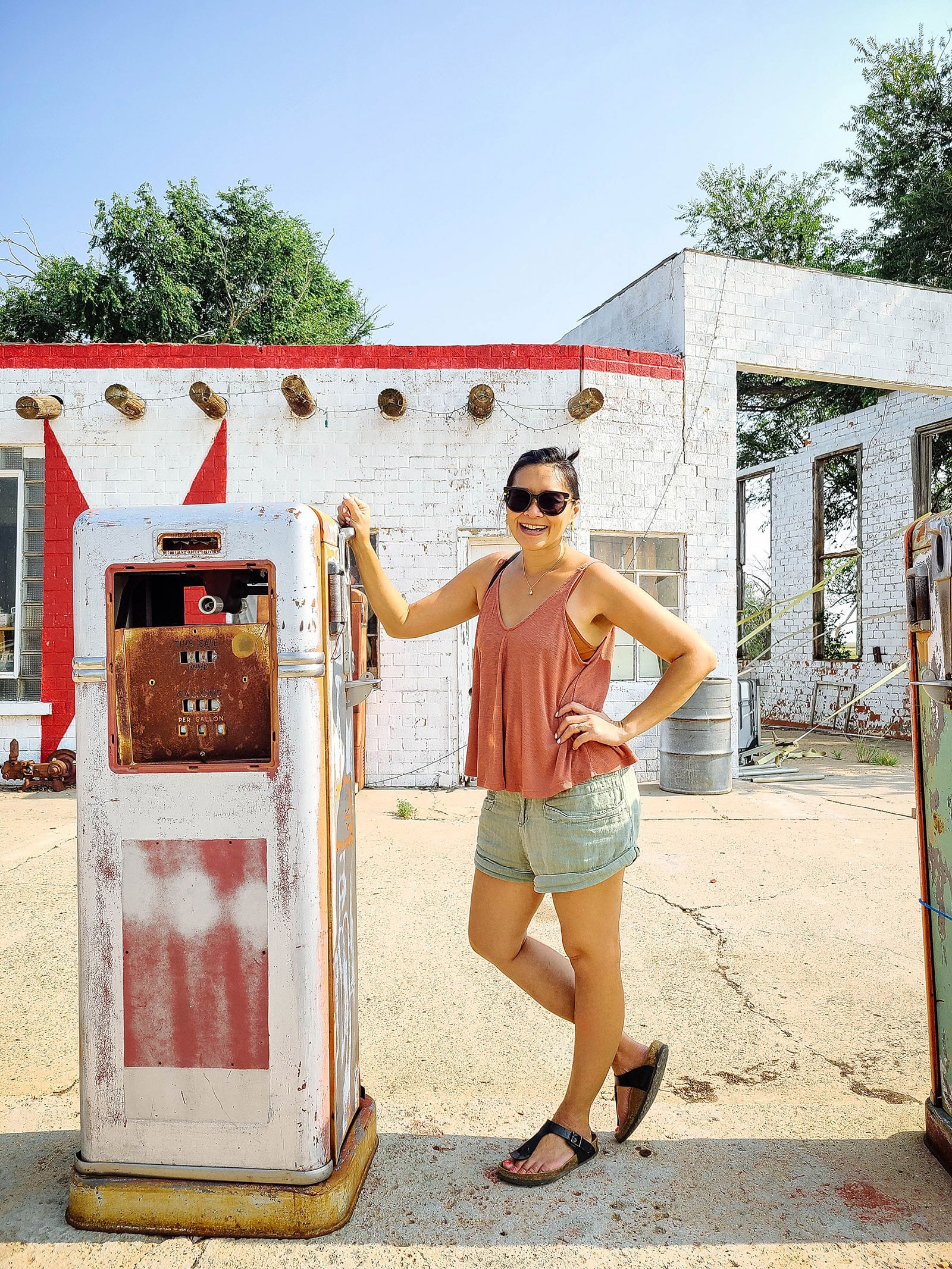 Linda Ly posing next to a vintage gas pump at The Bent Door Cafe in Texas