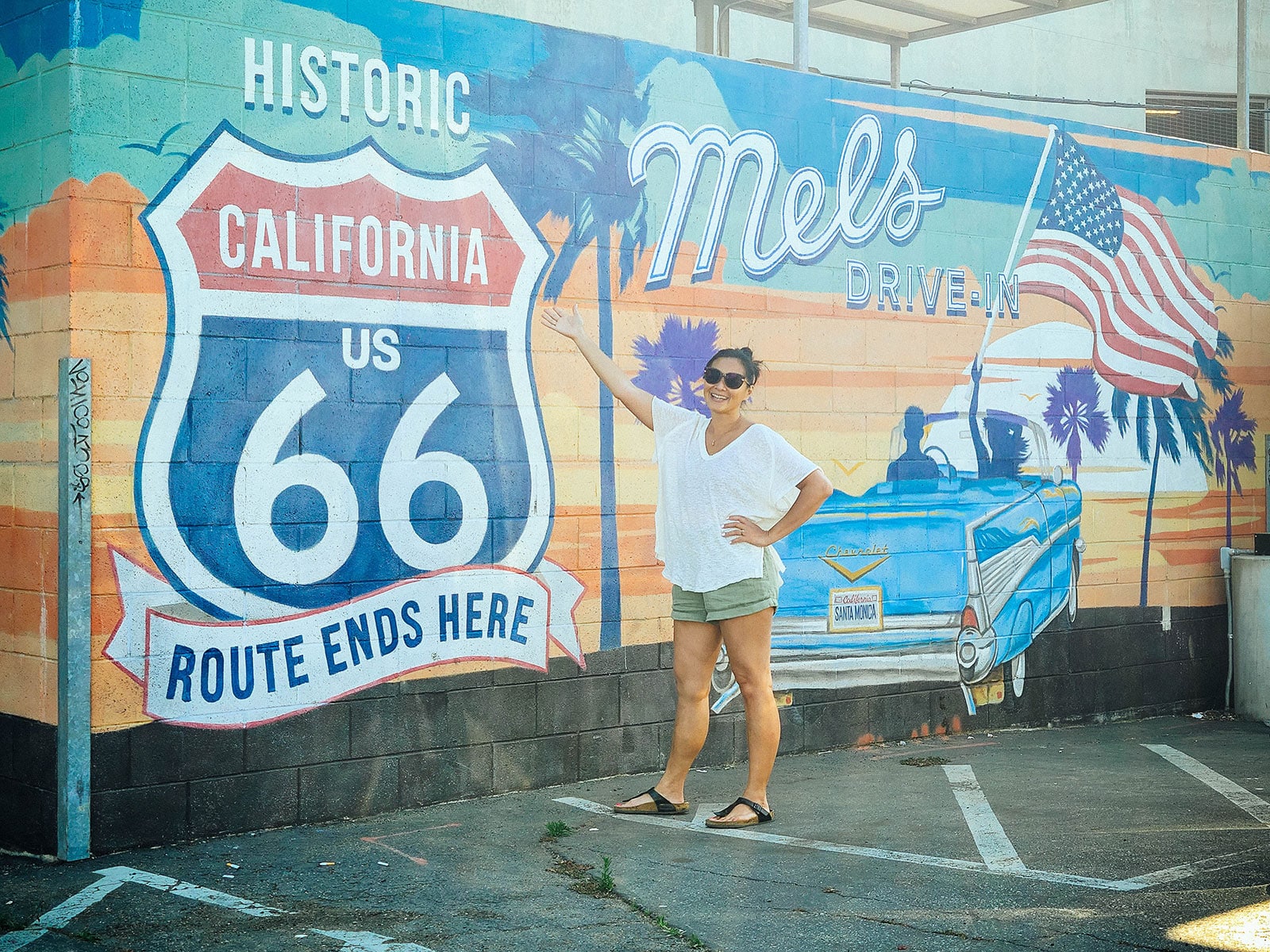 Linda Ly posing next to the Route Ends Here mural at Mel's Drive-In on Route 66 in Santa Monica, California