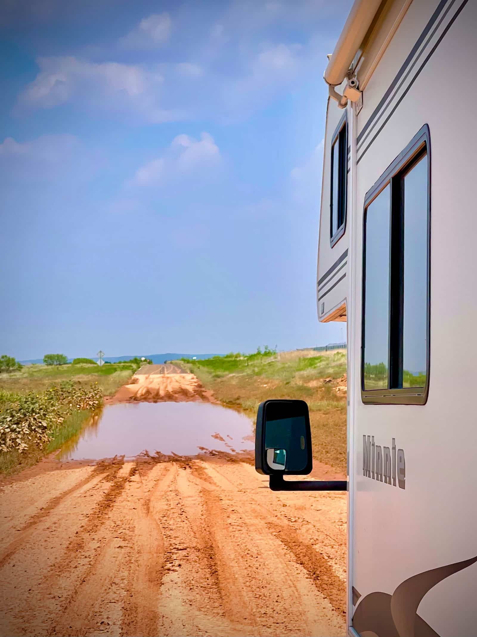 An RV driving up on a flooded dirt section of Historic Route 66 in New Mexico