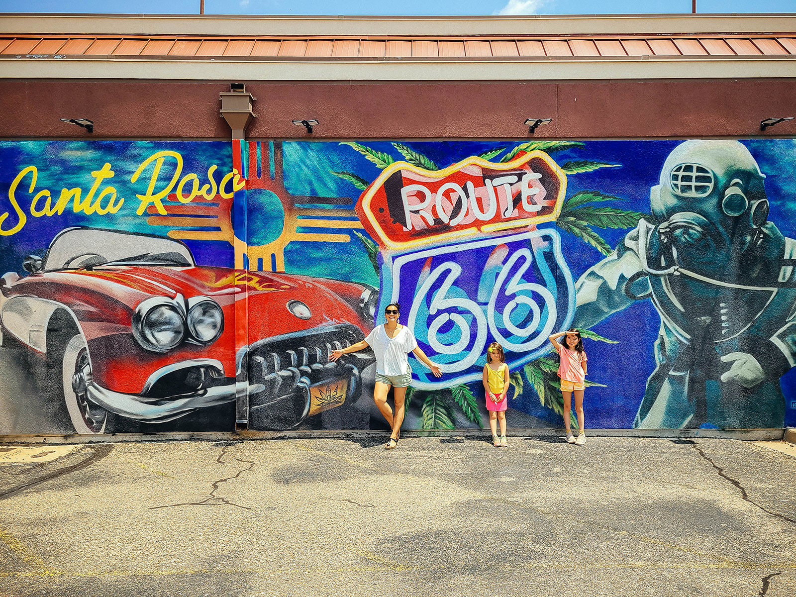 Linda Ly and two kids posing in front of a Route 66 mural in Santa Rosa, NM